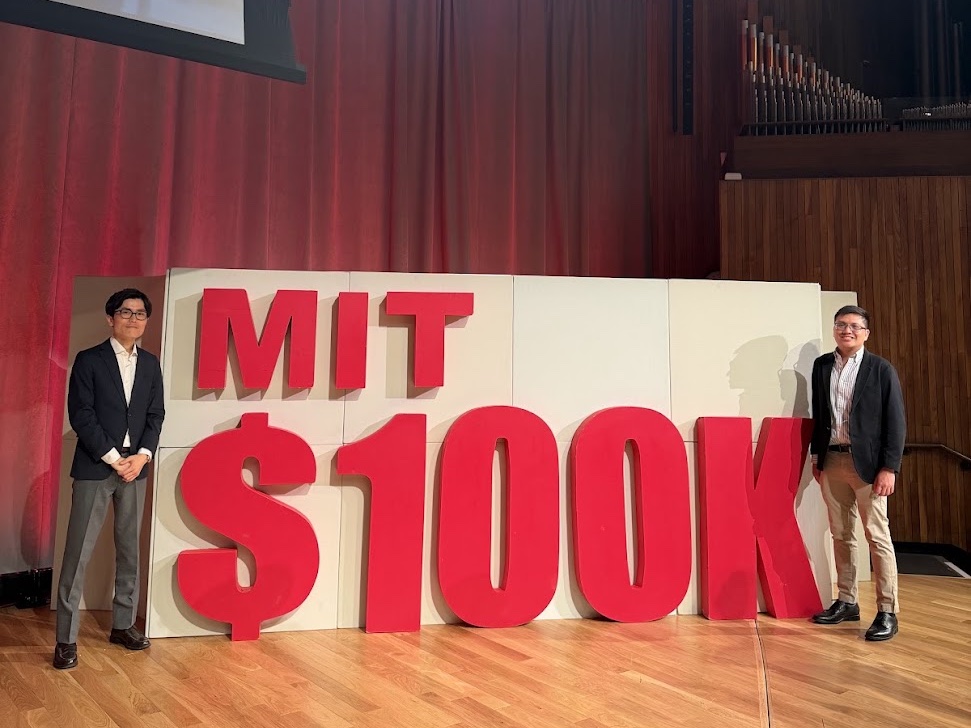 Co-founders Hiro Ogasawara and Rowell Castro on stage beside the MIT $100K sign